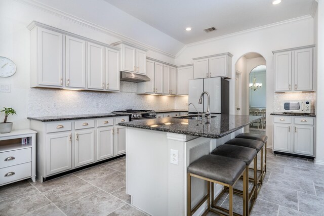 kitchen featuring sink, vaulted ceiling, a breakfast bar area, a center island with sink, and appliances with stainless steel finishes