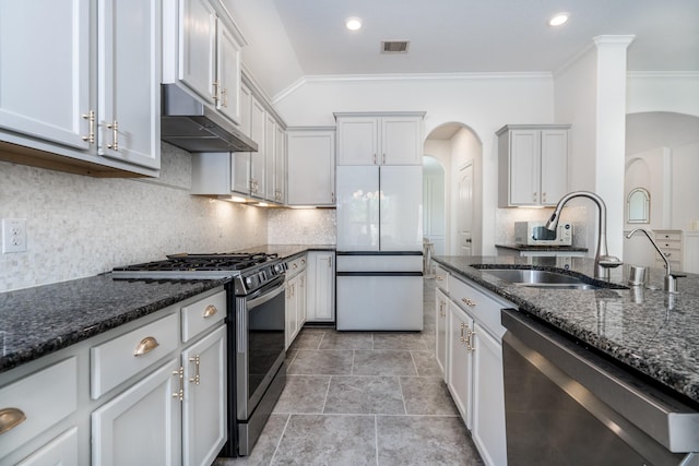 kitchen with white cabinets, sink, dark stone countertops, ornamental molding, and stainless steel appliances