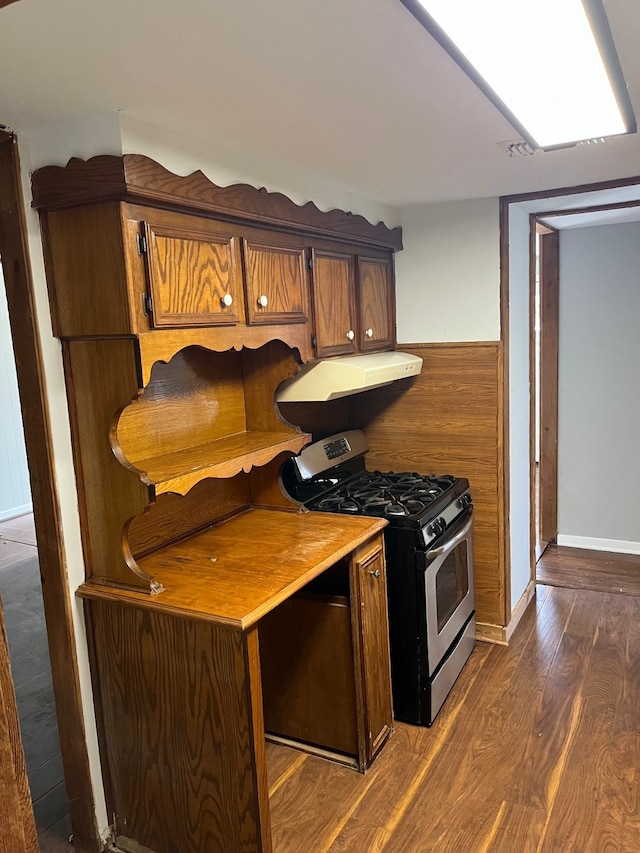 kitchen with stainless steel gas stove, dark wood-type flooring, and exhaust hood