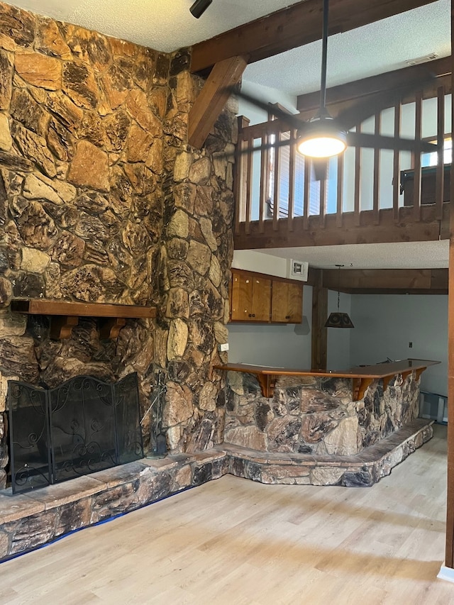 unfurnished living room with vaulted ceiling with beams, light hardwood / wood-style floors, and a fireplace