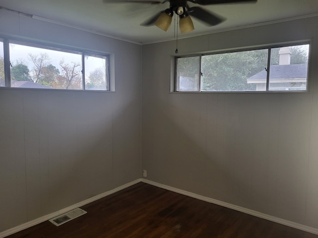 empty room featuring ceiling fan, dark hardwood / wood-style flooring, ornamental molding, and a wealth of natural light