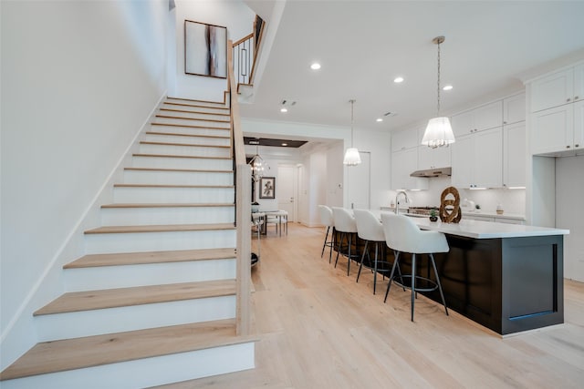 staircase with crown molding, hardwood / wood-style floors, and sink