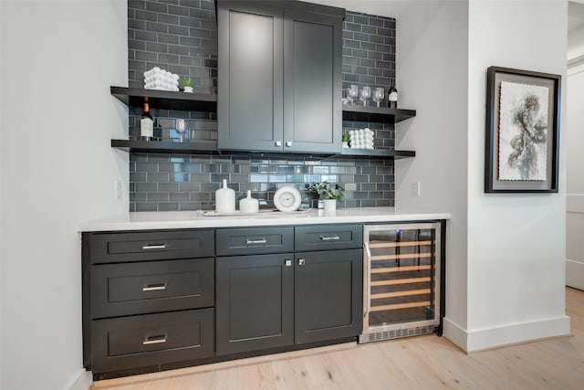 bar with decorative backsplash, light wood-type flooring, and wine cooler