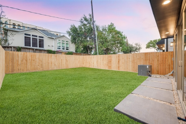 yard at dusk featuring central AC