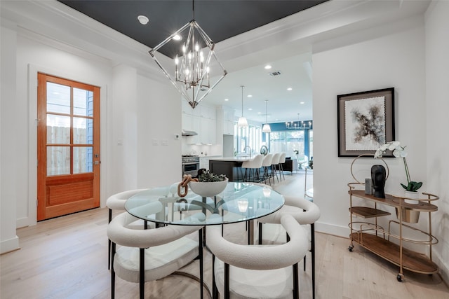 dining area with light wood-type flooring, an inviting chandelier, and sink