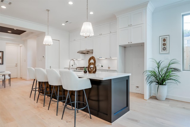 kitchen featuring white cabinetry, a kitchen island with sink, hanging light fixtures, and light hardwood / wood-style floors