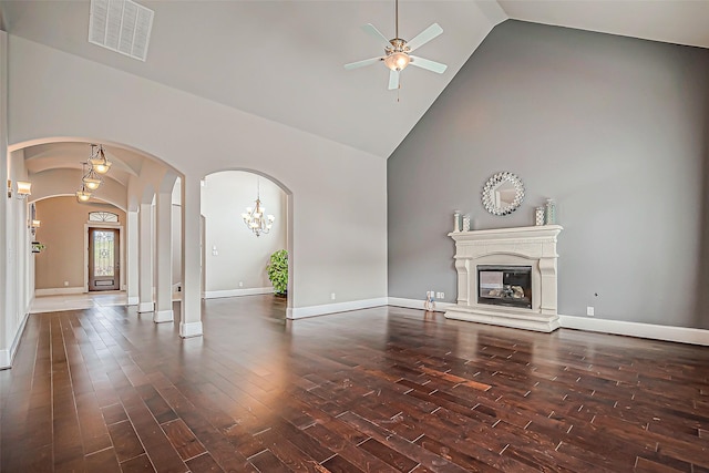 unfurnished living room featuring ceiling fan with notable chandelier, high vaulted ceiling, and dark wood-type flooring