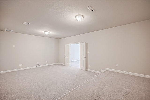 spare room with light colored carpet and a textured ceiling