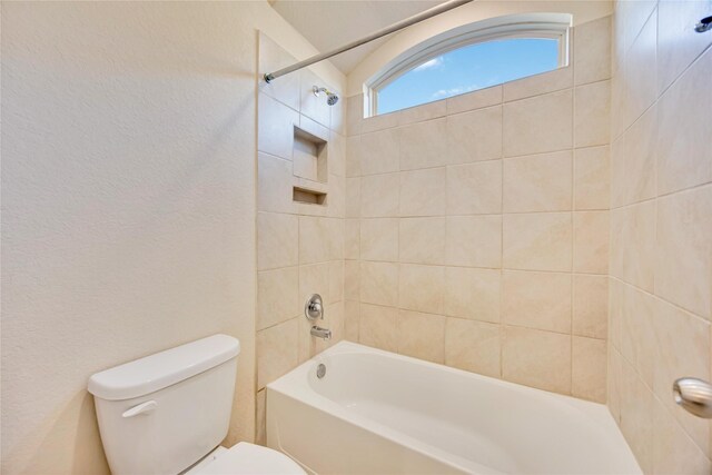 bathroom featuring toilet and tiled shower / bath