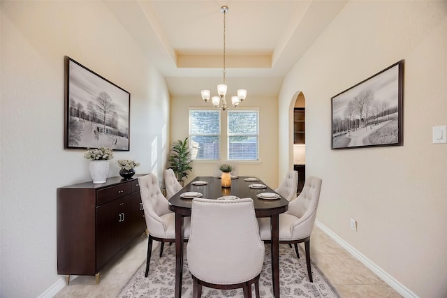 tiled dining area with a notable chandelier and a raised ceiling