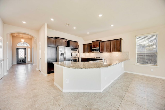 kitchen with light stone countertops, appliances with stainless steel finishes, decorative backsplash, and a wealth of natural light