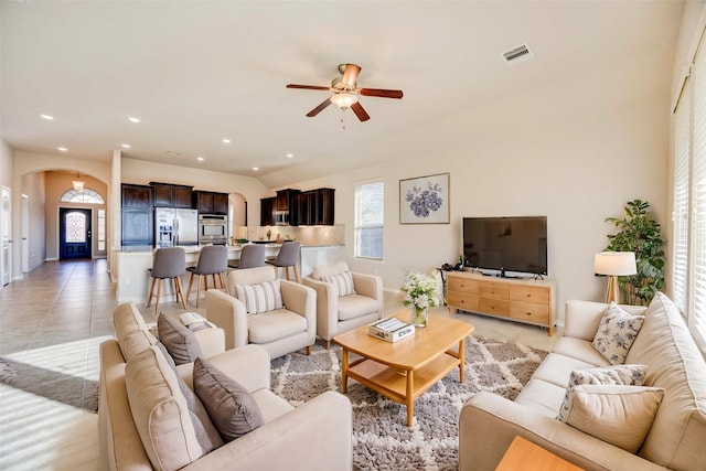 living room with ceiling fan, light tile patterned floors, and vaulted ceiling