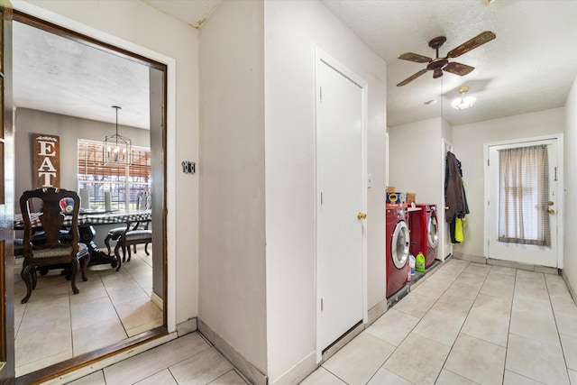 tiled entryway featuring ceiling fan with notable chandelier and washing machine and dryer