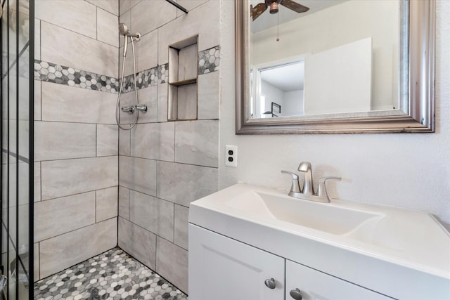 bathroom with a tile shower, ceiling fan, and vanity