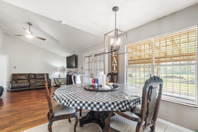 dining space featuring hardwood / wood-style flooring, ceiling fan with notable chandelier, and vaulted ceiling