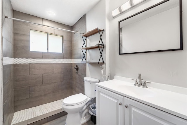 bathroom featuring vanity, toilet, and a tile shower