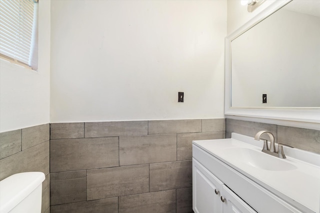 bathroom featuring vanity, toilet, and tile walls