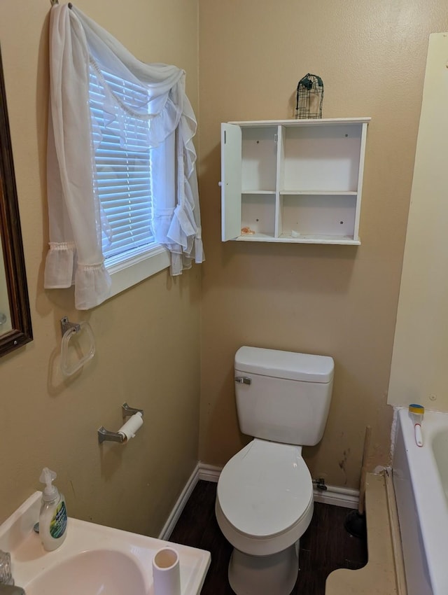 bathroom featuring toilet, wood-type flooring, and a bath