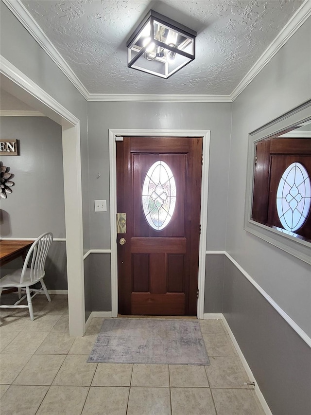 tiled foyer entrance with a textured ceiling and crown molding