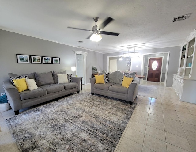 living room featuring built in shelves, ceiling fan, ornamental molding, a textured ceiling, and light tile patterned flooring