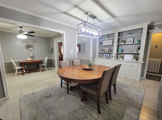 tiled dining space with ceiling fan, crown molding, built in features, and a textured ceiling