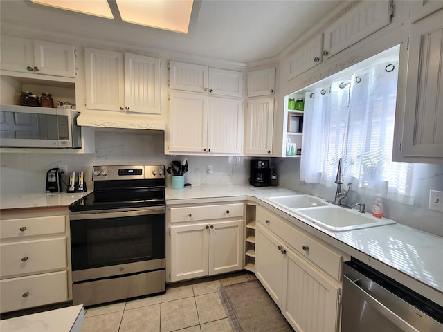 kitchen with appliances with stainless steel finishes, backsplash, sink, white cabinets, and light tile patterned flooring