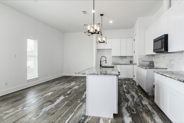 4702 Ward, Houston, TX 77021 - kitchen with black microwave, a chandelier, light stone counters, dark wood-style floors, and decorative backsplash