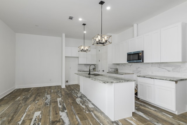4702 Ward, Houston, TX 77021 - kitchen with stainless steel microwave, a chandelier, light stone counters, decorative backsplash, and white cabinets