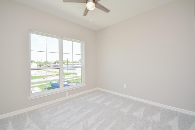 empty room with ceiling fan, light colored carpet, and a wealth of natural light