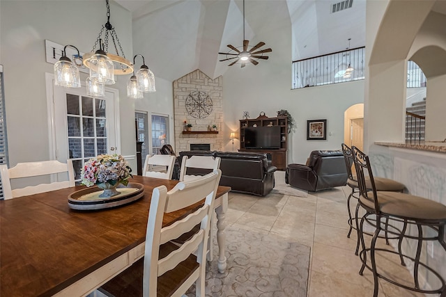 dining area featuring a fireplace, light tile patterned floors, high vaulted ceiling, and ceiling fan