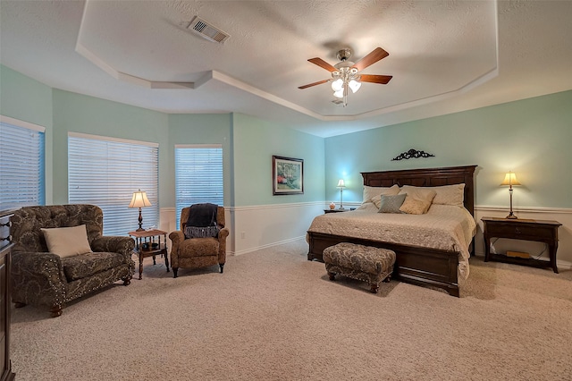 carpeted bedroom featuring a textured ceiling, a raised ceiling, and ceiling fan