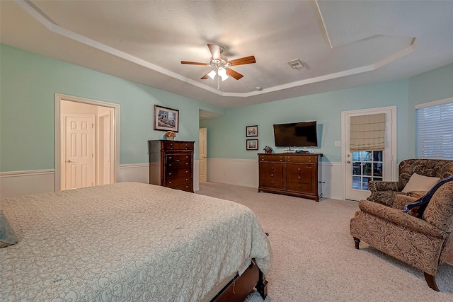 carpeted bedroom with access to exterior, ceiling fan, and a raised ceiling