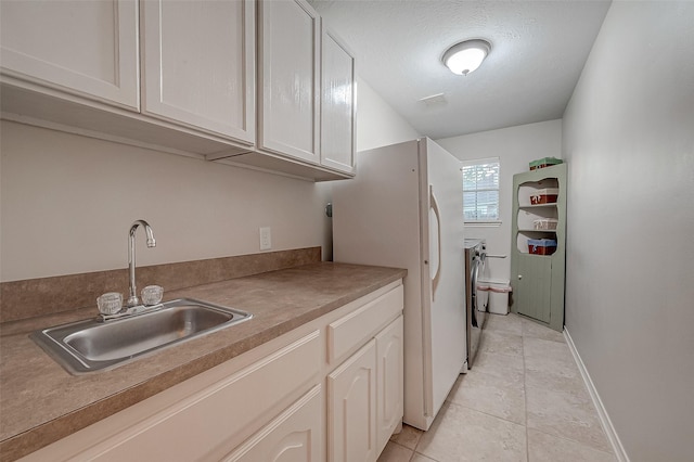 kitchen with washer and clothes dryer, sink, white cabinets, and white refrigerator