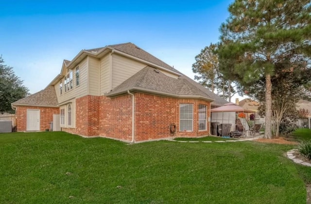 back of property featuring a gazebo and a lawn