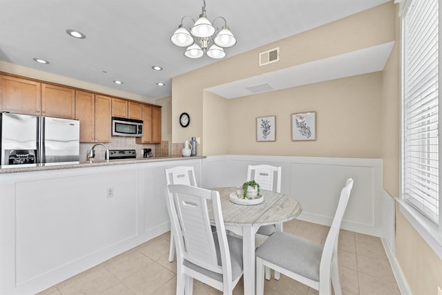 dining area with light tile patterned floors, an inviting chandelier, and sink