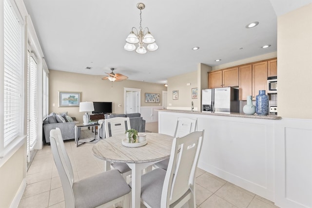 dining space featuring ceiling fan with notable chandelier, light tile patterned floors, and sink