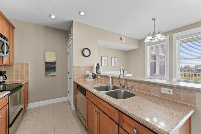 kitchen with sink, light stone countertops, appliances with stainless steel finishes, tasteful backsplash, and a chandelier