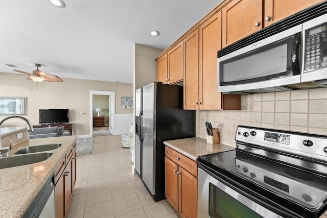 kitchen with ceiling fan, sink, light stone counters, light tile patterned floors, and appliances with stainless steel finishes