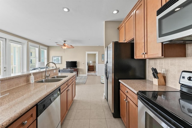 kitchen featuring decorative backsplash, appliances with stainless steel finishes, light stone counters, ceiling fan, and sink