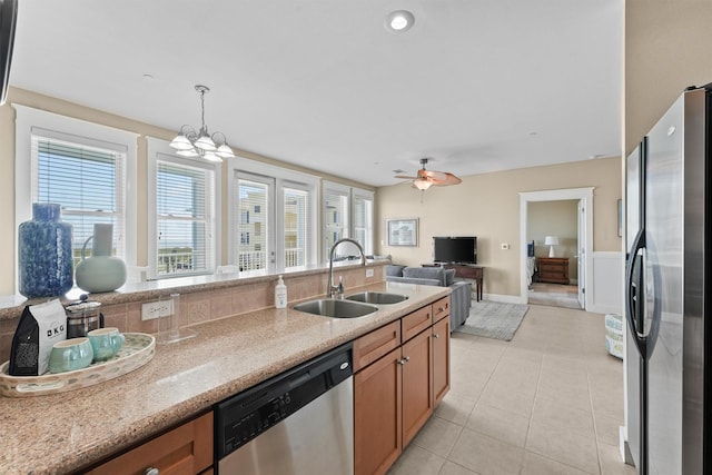 kitchen with sink, hanging light fixtures, stainless steel appliances, light stone counters, and light tile patterned flooring