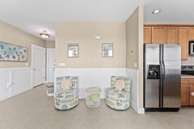 kitchen featuring backsplash, light tile patterned floors, and stainless steel appliances