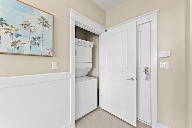 laundry area featuring light tile patterned floors and stacked washing maching and dryer