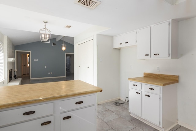 kitchen with pendant lighting, light tile patterned flooring, white cabinets, and vaulted ceiling