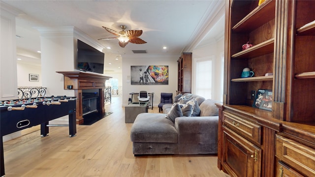 living room featuring crown molding, ceiling fan, and light wood-type flooring