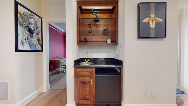 bar with ornamental molding, sink, and light hardwood / wood-style flooring