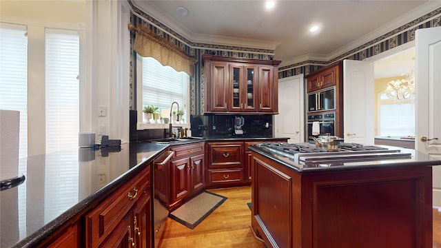 kitchen with sink, stainless steel appliances, light hardwood / wood-style floors, a kitchen island, and ornamental molding