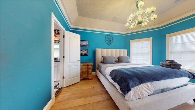 bedroom featuring light hardwood / wood-style flooring, a raised ceiling, and a notable chandelier