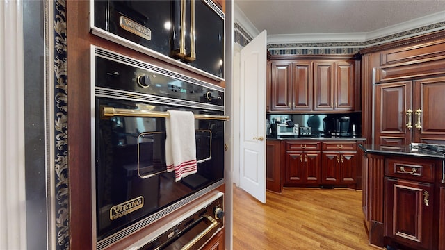 kitchen with oven, ornamental molding, and light hardwood / wood-style flooring