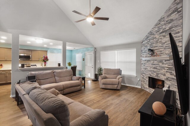 living room featuring a healthy amount of sunlight, a fireplace, high vaulted ceiling, and light hardwood / wood-style flooring