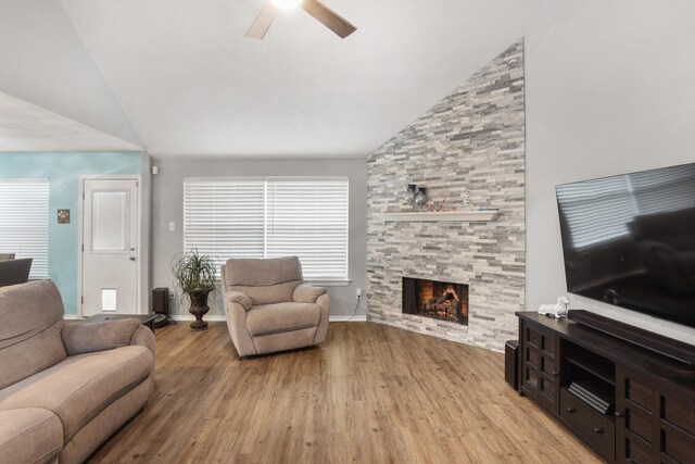 living room featuring lofted ceiling, a fireplace, ceiling fan, and light wood-type flooring